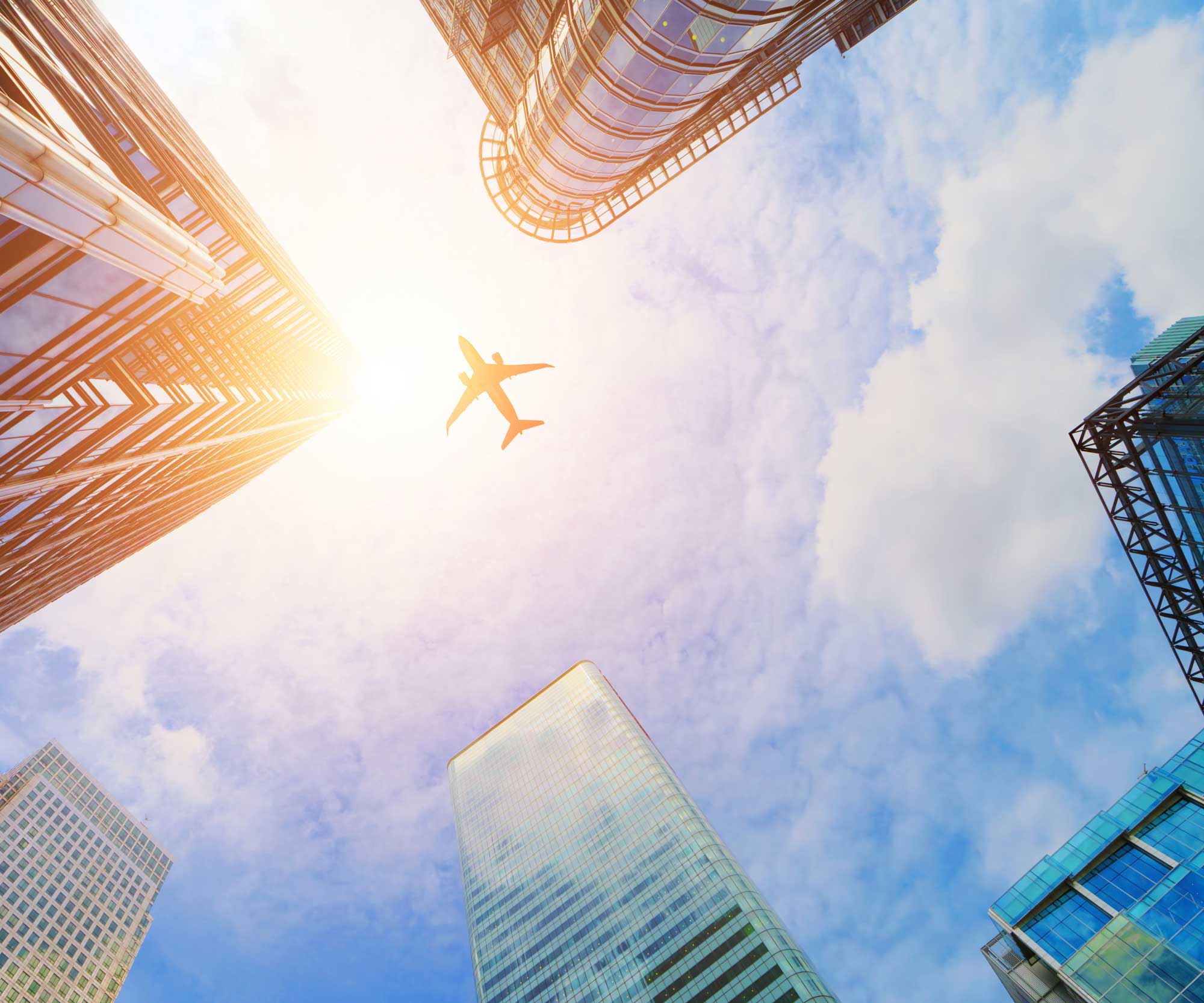 person sitting on floor next to a suitcase and holding phone, passport and plane ticket